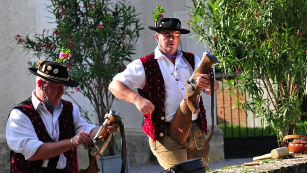 Zwei Männer in Tracht hantieren mit traditionellen Gewehren.
