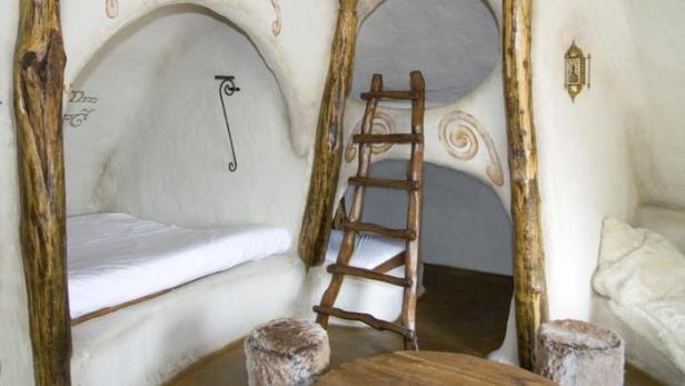 Ein Zimmer in einem ungewöhnlichen Haus mit Betten, einer Leiter und runden Hockern.