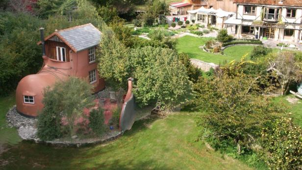 Ein Haus in Form eines Stiefels in einer grünen Gartenanlage.