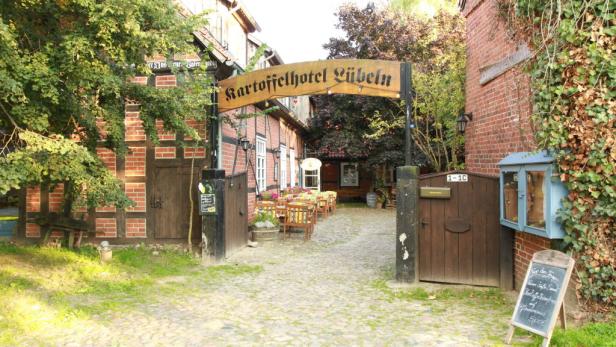 Der Eingang zum Kartoffelhotel Lübeln mit einem Schild über dem Torbogen.