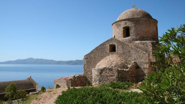 Eine alte Steinkirche mit Kuppel überblickt das Meer.