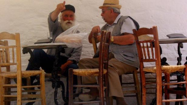 Zwei ältere Männer sitzen an einem Tisch und unterhalten sich.