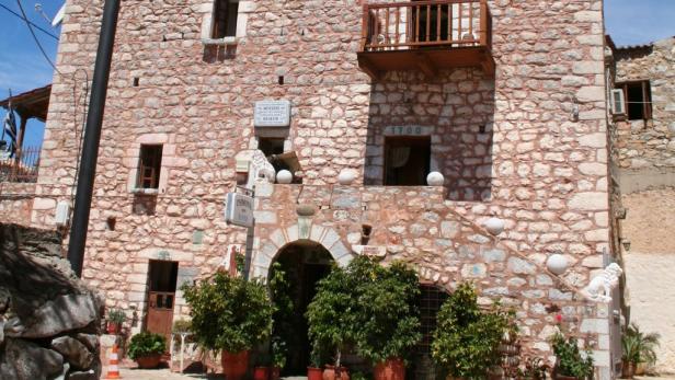 Ein historisches Steingebäude mit einem kleinen Balkon und einem Torbogen-Eingang.