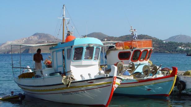 Zwei Fischerboote liegen vor einer griechischen Insel vor Anker.
