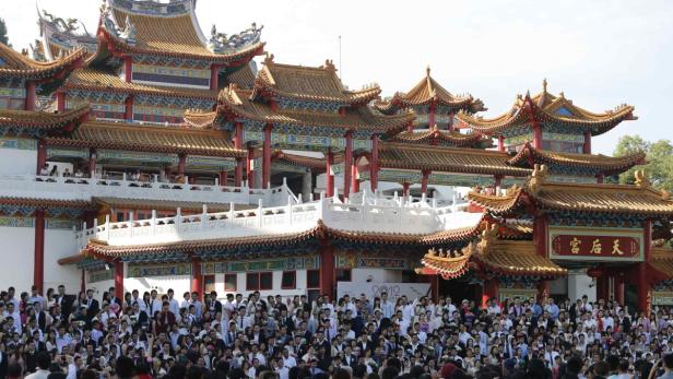 Eine große Menschenmenge versammelt sich vor einem verzierten chinesischen Tempel.