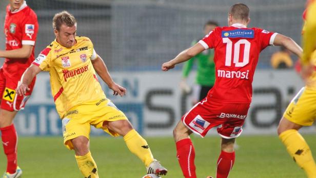 Zwei Fußballspieler kämpfen um den Ball während eines Spiels.