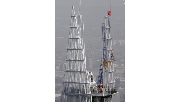 Bauarbeiter arbeiten an der Spitze eines hohen Gebäudes, möglicherweise „The Shard“ in London.