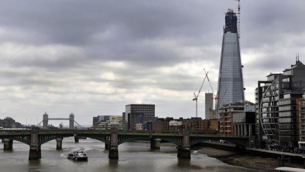 Blick auf die Skyline von London mit der Tower Bridge und The Shard unter bewölktem Himmel.