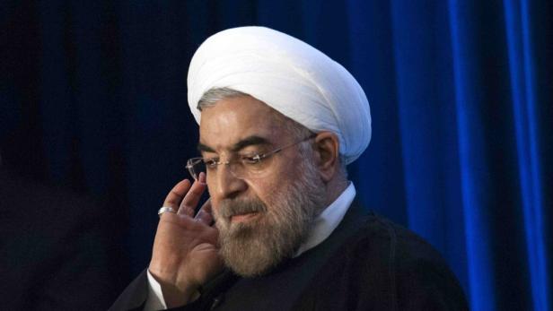 Hassan Rohani mit Turban und Brille vor einem blauen Hintergrund.