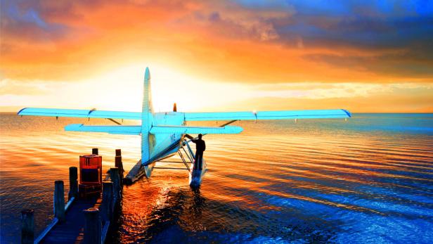 Ein Wasserflugzeug liegt an einem Steg bei Sonnenuntergang vor Anker.