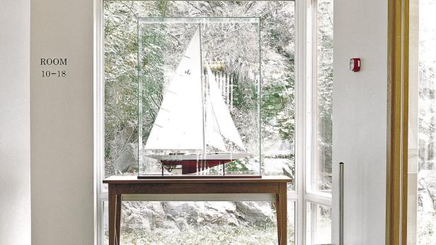 Ein Modellboot steht in einer Vitrine vor einem Fenster.