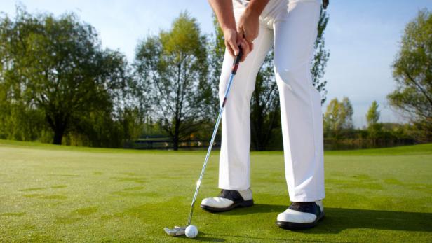 Ein Golfer puttet auf einem grünen Golfplatz.