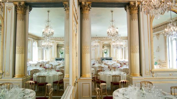 Ein elegant dekorierter Ballsaal mit Tischen und Kristalllüstern.