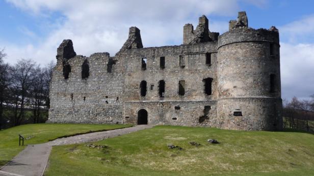 Die Ruine eines alten Schlosses auf einem grünen Hügel.
