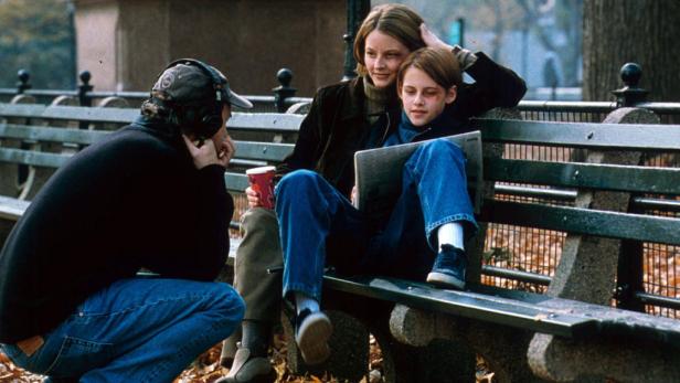 Kristen Stewart sitzt mit Diane Lane auf einer Parkbank, während ein Mann zusieht.