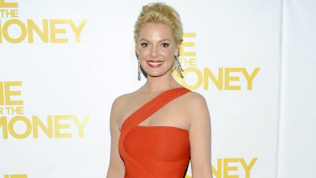 Katherine Heigl in einem orangefarbenen Kleid auf einem roten Teppich.
