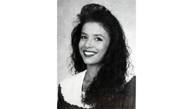 Schwarzweißporträt einer jungen, lächelnden Frau mit dunklem, lockigem Haar.