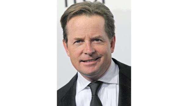Ein Porträt von Michael J. Fox in einem schwarzen Anzug mit Krawatte.