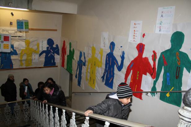 Eine Gruppe von Kindern geht eine Treppe in einem Gebäude hinunter, dekoriert mit bunten Silhouetten an der Wand.