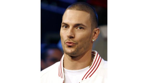 Ein Mann mit kurzem Haar und Ohrring blickt in die Kamera.