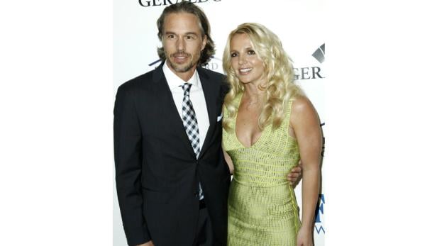 Britney Spears posiert mit einem Mann im Anzug auf einem Event.