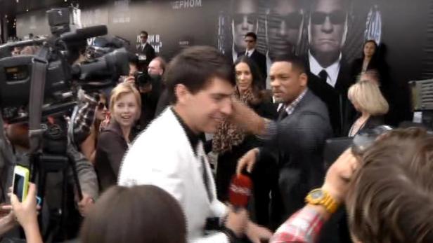 Will Smith bei einer Filmpremiere, umringt von Fans und Reportern.