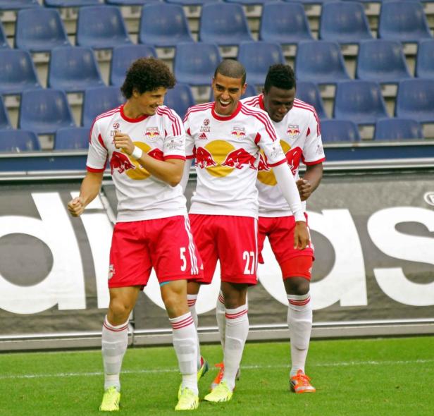 Drei Fußballspieler von RB Leipzig jubeln auf dem Rasen.