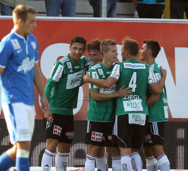 Eine Gruppe Fußballspieler in grünen Trikots umarmt sich auf dem Spielfeld.