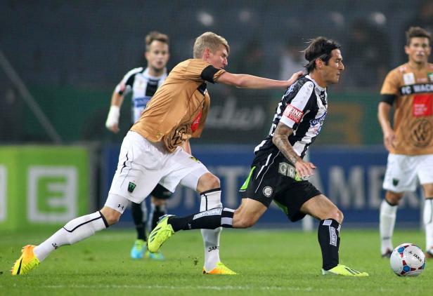 Zwei Fußballspieler kämpfen um den Ball auf dem Spielfeld.