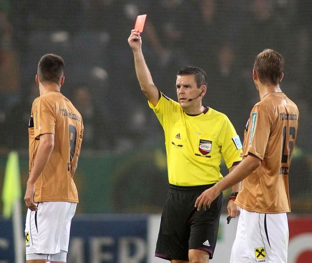 Ein Schiedsrichter zeigt während eines Fußballspiels die Rote Karte.