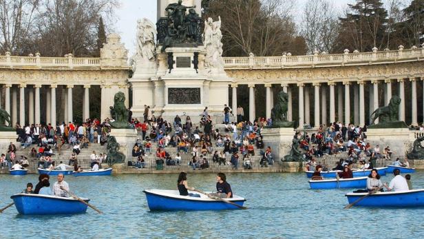 Menschen fahren mit Ruderbooten auf dem See im Parque del Retiro in Madrid.