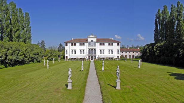 Ein großes, weißes Gebäude mit Statuen im Garten.