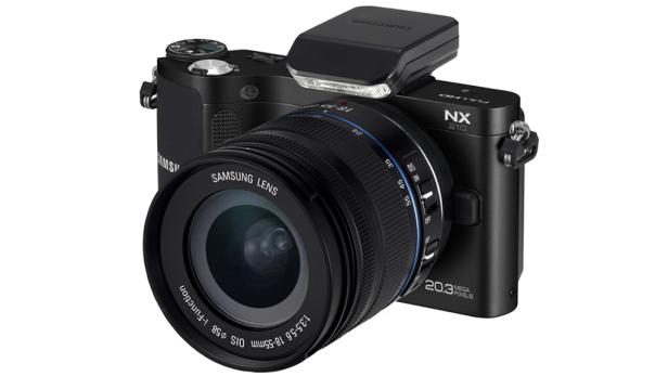 Eine schwarze Samsung NX210 Systemkamera mit aufgesetztem Blitzgerät.