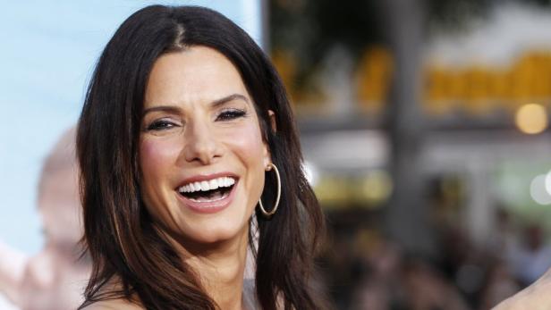 Sandra Bullock lächelt mit goldenen Creolen in die Kamera.