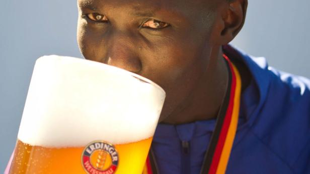 Ein Sportler mit einer Medaille trinkt ein Erdinger Weißbier.