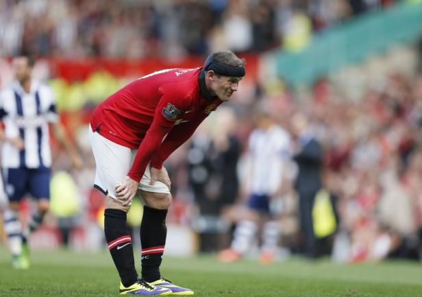 Wayne Rooney, mit Kopfschutz, stützt sich erschöpft auf seine Knie während eines Fußballspiels.