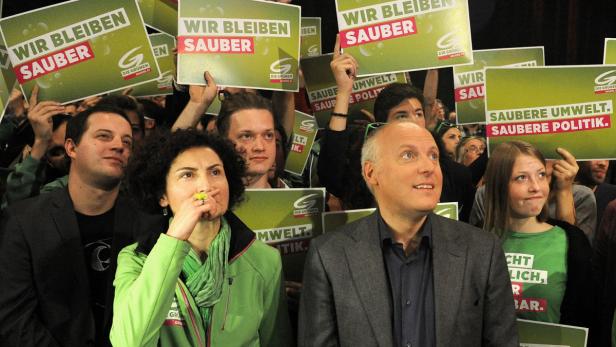 Menschen halten Schilder mit der Aufschrift „Wir bleiben sauber“ und „Saubere Umwelt. Saubere Politik.“ hoch.