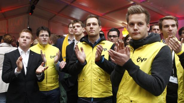 Eine Gruppe junger Männer in gelben ÖVP-Westen klatscht Beifall.