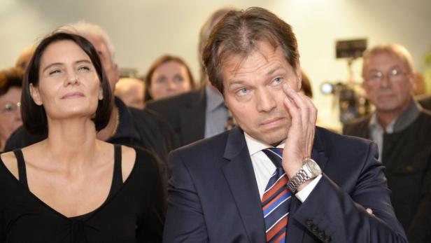 Ein Mann im Anzug wischt sich eine Träne aus dem Auge, während eine Frau daneben nach oben blickt.