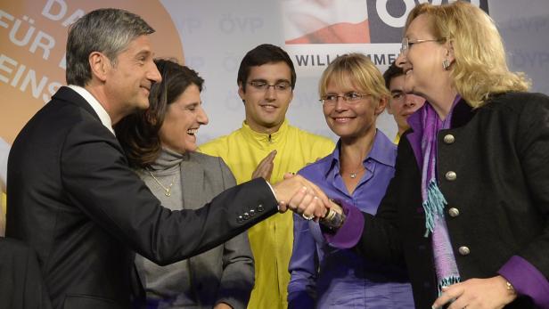 Mehrere Personen, darunter zwei im Vordergrund, schütteln sich die Hände.