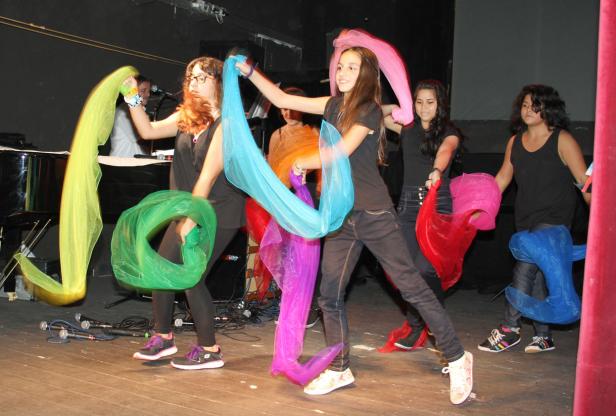 Eine Gruppe junger Frauen tritt mit bunten Tüchern auf einer Bühne auf.