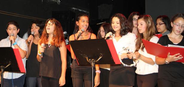 Eine Gruppe Jugendlicher singt gemeinsam in einem Chor vor Notenständern.