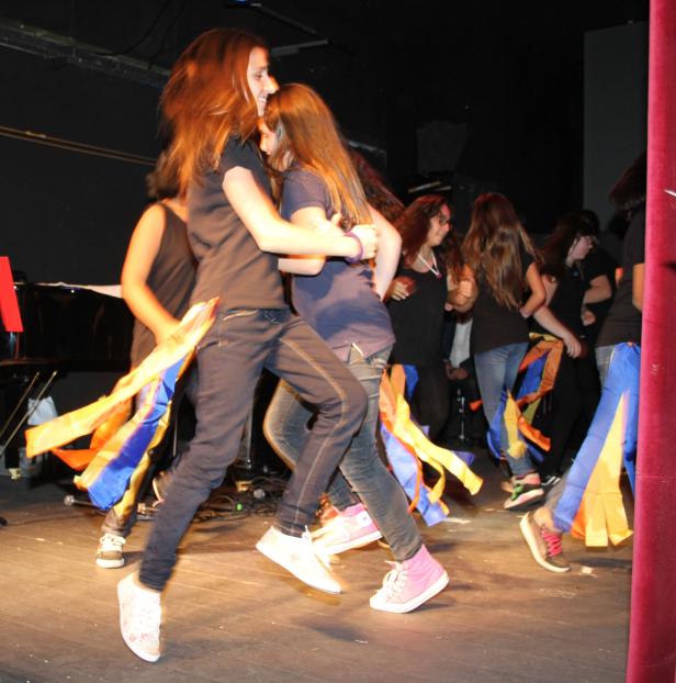 Eine Gruppe junger Frauen tanzt mit bunten Bändern auf einer Bühne.