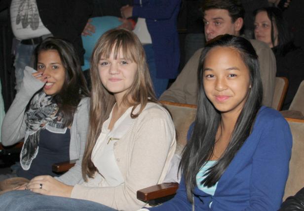 Drei junge Frauen sitzen nebeneinander in einem Theatersaal.
