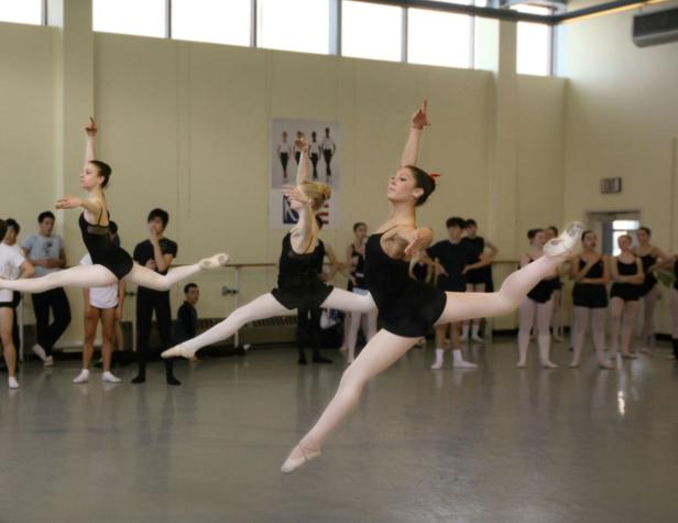 Mehrere Ballerinen springen in einem Tanzstudio in die Luft.