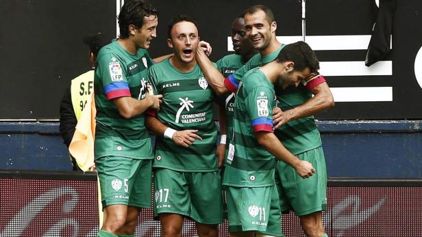 Eine Gruppe von Fußballspielern in grünen Trikots feiert ein Tor.
