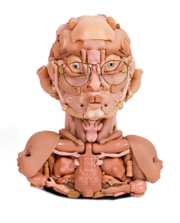Eine Skulptur einer Büste, die aus Teilen von Babypuppen und einer Brille besteht.