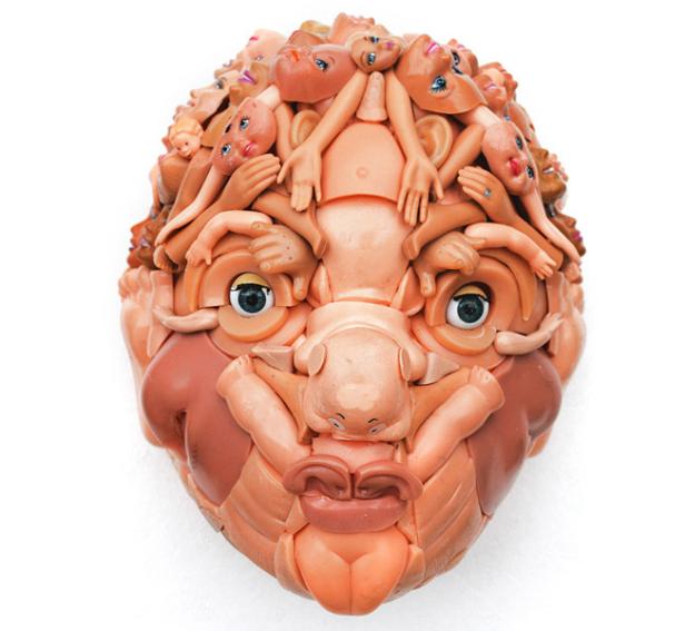 Eine skulpturartige Maske, geformt aus Teilen von Babypuppen.