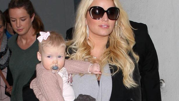 Jessica Simpson trägt ihr Kind mit Schnuller und Schleife im Haar.