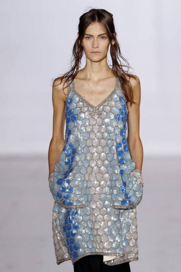 Eine Frau trägt ein ärmelloses, blau-silbernes Paillettenkleid.